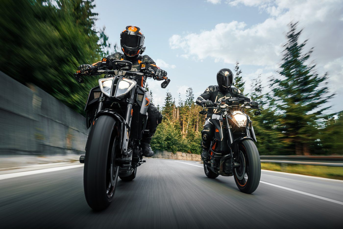 Dva motocyklisté v jízdě na silnici v lese