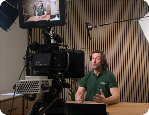 Muž v zelenej polokošeli hovorí do kamery pri natáčaní videa v kancelárii s dreveným obkladom, tepelné čerpadlá